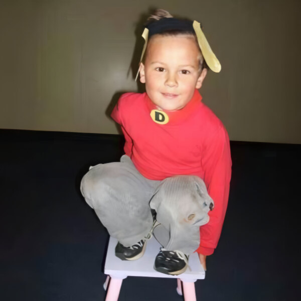 Child in costume sitting on stool indoors.