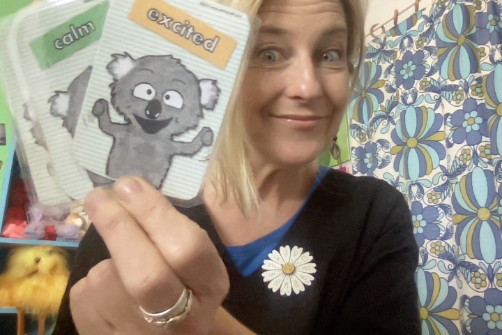 Smiling person holding emotion cards, calm and excited.